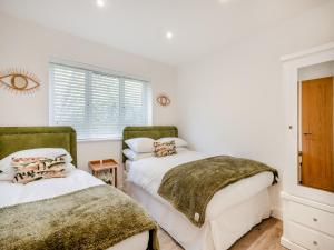 two beds in a room with white walls and a window at High Garden in Belton