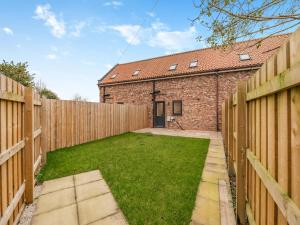a backyard with a fence and a brick building at Salix 3 - Uk46115 in Wigginton
