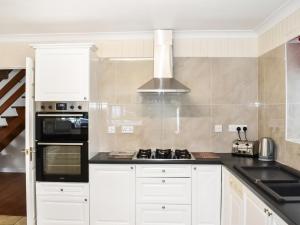 a kitchen with white cabinets and a stove top oven at Ffin Yr Afon - Ukc6907 in Towyn