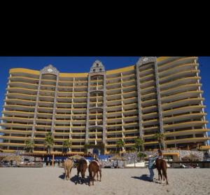 a hotel on the beach with horses in front of it at Sonoran Sky Resort Vista a Playa Azul in Puerto Peñasco