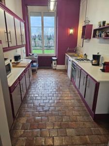 kuchnia z fioletowymi ścianami i ceglaną podłogą w obiekcie La Jonchere 