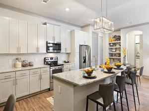 una cocina con armarios blancos y una isla de cocina con sillas en Luxury 2br Apartment (Buckhead), en Atlanta