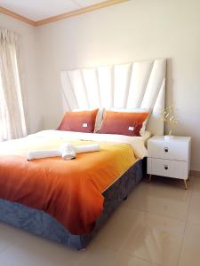 um quarto com uma cama grande e um cobertor laranja em La casa de Miah em Sandton