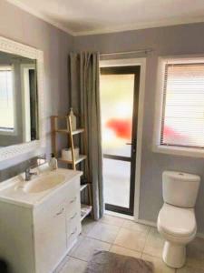 a bathroom with a toilet and a sink and a window at Country Life in Tauranga