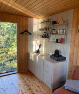 a kitchen with a counter in a room with a window at Velkommen til Finnskogen og minihytta Rimbila in Kongsvinger