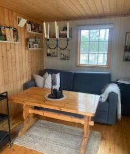 a living room with a wooden table and a blue couch at Velkommen til Finnskogen og minihytta Rimbila in Kongsvinger