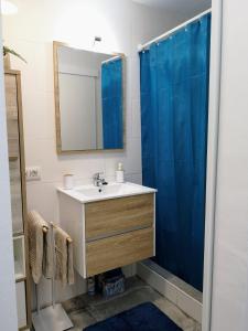 a bathroom with a sink and a blue shower curtain at Apartamento OCEAN PEARL in Corralejo