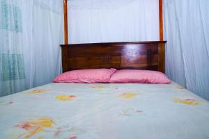 uma cama com almofadas cor-de-rosa e uma cabeceira de madeira em hikka T&O nature villa em Hikkaduwa
