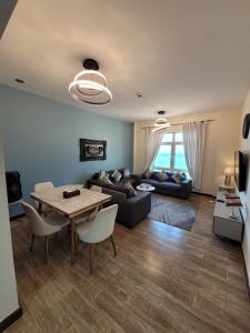 Royal Beach Apartment في King Abdullah Economic City: غرفة معيشة مع أريكة وطاولة