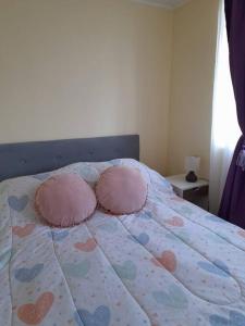 Una cama con almohadas rosas y corazones. en Apartamento Viña del Mar, en Viña del Mar