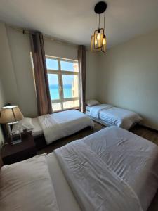 a bedroom with three beds and a window at Royal Beach Apartment in King Abdullah Economic City