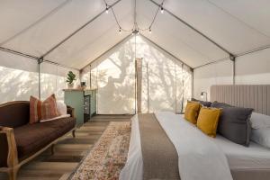 a bedroom with a bed and a couch in a tent at Oak Retreat Glamping With Private Hot tub in Luckenbach