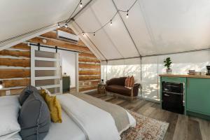 a bedroom with a bed in a room with wooden walls at Oak Retreat Glamping With Private Hot tub in Luckenbach