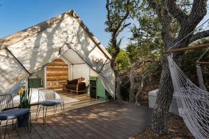 a tent with a hammock on a deck at Oak Retreat Glamping With Private Hot tub in Luckenbach