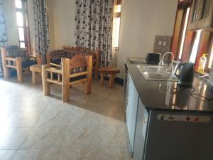 a kitchen with a sink and a table and a chair at 2 Envubu Cottage - Benanda Forest Resort in Masaka