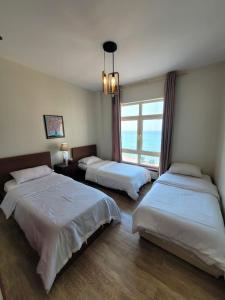 Habitación de hotel con 2 camas y ventana en Royal Beach Apartment en King Abdullah Economic City