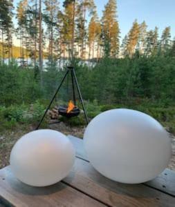 dos esferas blancas sentadas en una mesa de picnic con fuego en Off-grid minihus på Finnskogen., en Kongsvinger