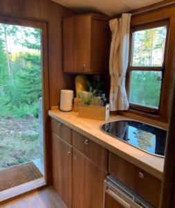 una pequeña cocina con fregadero y ventana en Off-grid minihus på Finnskogen., en Kongsvinger