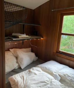 1 dormitorio con cama, ventana y estante en Off-grid minihus på Finnskogen., en Kongsvinger