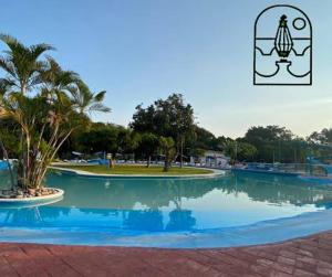 uma grande piscina de água com palmeiras num parque em Rústica y armoniosa casa de campo cerca de las estacas em Ticumán
