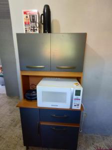 a microwave sitting on top of a desk with a cabinet at SÃO PEDRO DA ALDEIA À 15 MINUTOS DE CABO FRIO in São Pedro da Aldeia +11 photos