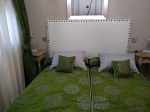 a bedroom with a bed with green sheets and pillows at Maria Santian in Arcones