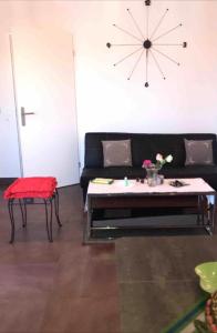 ein Wohnzimmer mit einem schwarzen Sofa und einem Tisch in der Unterkunft Appartement meublé in Montpellier