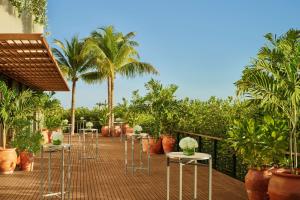 a row of tables and chairs on a deck with palm trees at The Riviera Maya EDITION at Kanai in Playa del Carmen
