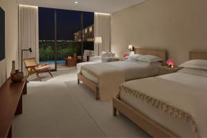 a large hotel room with two beds and a balcony at The Riviera Maya EDITION at Kanai in Playa del Carmen