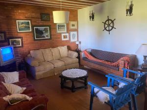 ein Wohnzimmer mit einem Sofa und einem TV in der Unterkunft Casa de seis suites na beira do mar in Rio das Ostras