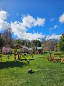 a park with benches and a swing set in the grass at La Yaya - Villa Turismo in El Bolsón