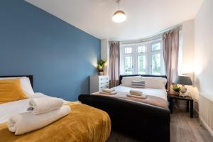 1 dormitorio con 2 camas y pared azul en Accessible 3-bedroom bungalow with patio +driveway, en Southampton