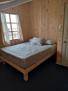 uma cama num quarto de madeira com uma janela em Verdeagua Hostal em Chaitén