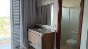 a bathroom with a sink and a toilet and a mirror at Pousada Mandala Botucatu in Botucatu