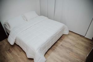 Cama blanca en habitación con suelo de madera en Big Comfort Apartment en Valledupar