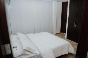Big Comfort Apartment في فاليدوبار: غرفة نوم بسرير أبيض مع شراشف بيضاء