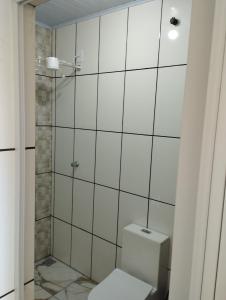 a white bathroom with a toilet and a shower at Pousada São Benedito in Cachoeira Paulista