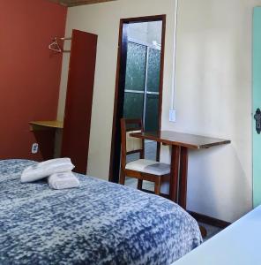 Cette chambre comprend un lit, un bureau et une table. dans l'établissement Chacara Descanso do Rei, à Vinhedo