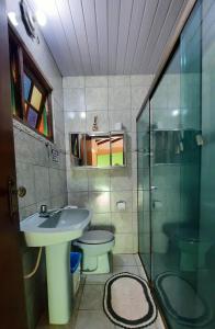 La salle de bains est pourvue d'un lavabo, de toilettes et d'une douche en verre. dans l'établissement Chacara Descanso do Rei, à Vinhedo