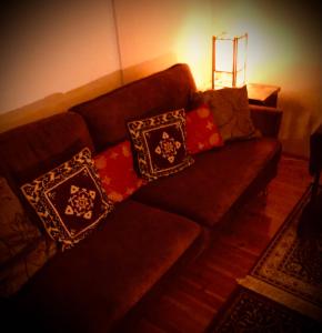 a brown couch with pillows on it in a living room at Meditation Room with light bfast - private toilet, no shower in Rovaniemi
