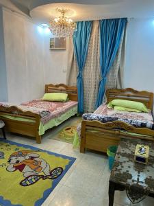 a bedroom with two beds and a chandelier at شقة للايجار مفروشة بالكامل in Cairo