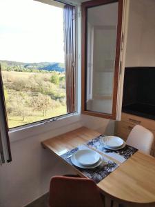einen Tisch mit zwei Tellern darauf in einem Zimmer mit Fenster in der Unterkunft Le panorama époustouflant " climatisé" in Gréoux-les-Bains