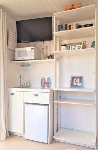 cocina con estanterías blancas y microondas en SUITE DA FRENTE COM COPA, WIFI E ACESSO INDEPENDENTE, en Búzios 7 fotos más