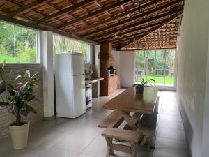 a kitchen with a white refrigerator and a table at Sítio - casa de campo in Domingos Martins