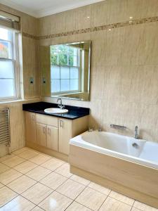 uma grande casa de banho com banheira e lavatório em Stunning Thameside Apartment em Henley on Thames