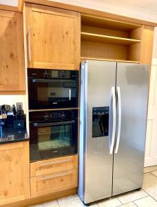 a stainless steel refrigerator in a kitchen with wooden cabinets at Stunning Thameside Apartment in Henley on Thames