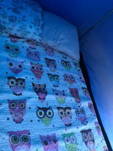 a blue comforter with owls on a bed at Camping beira mar in Bertioga