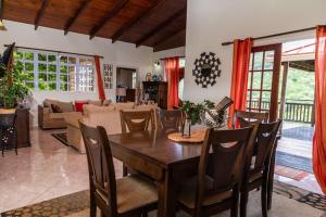 a dining room and living room with a table and chairs at Lush Green Villa with mountain and garden view in Castries