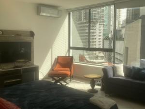 a bedroom with a couch and a chair and a window at Habitación Frente a la Bahia con baño privado in Panama City