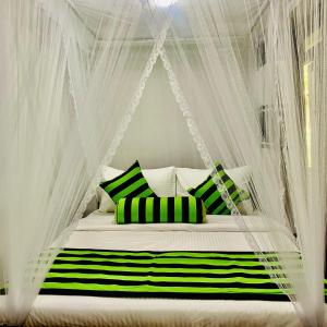 een bed met een baldakijn met groene en witte kussens bij Ella South Star in Ella